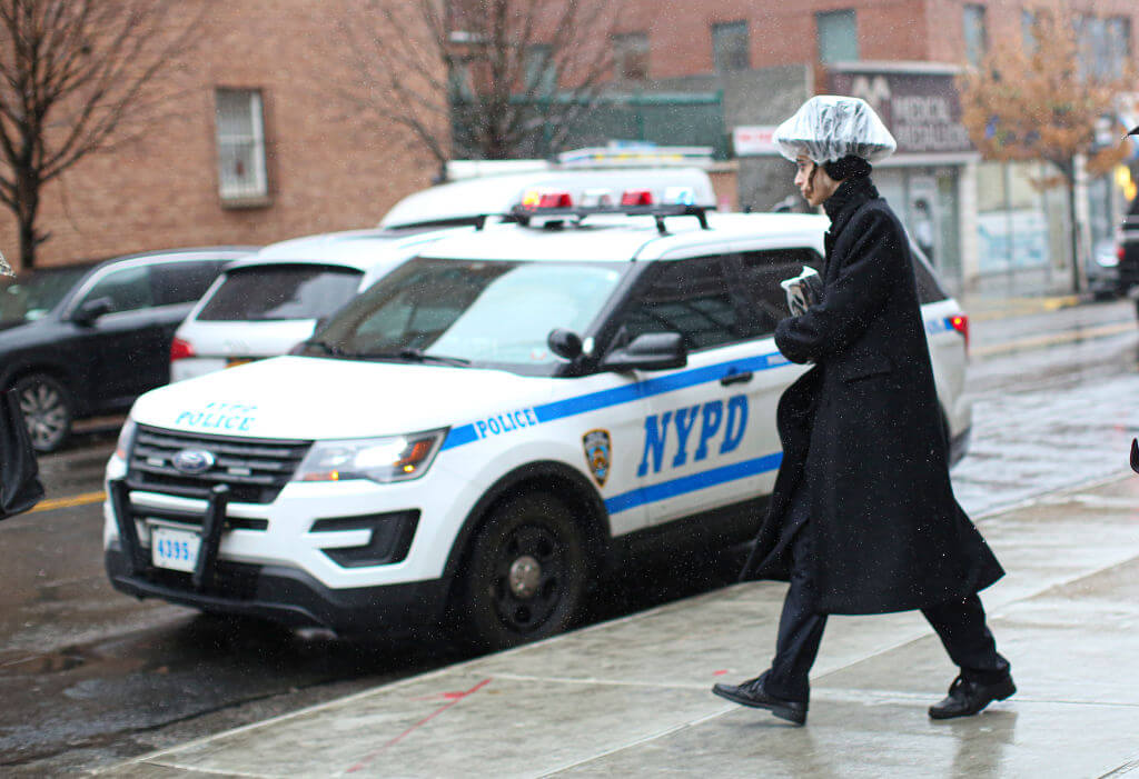 A man walks past a New York City Police Department car in Brooklyn. 