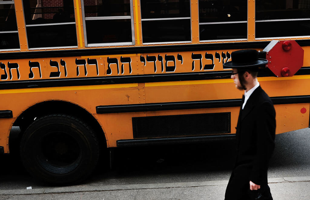 A Hasidic man passes a school bus in a Jewish Orthodox neighborhood in Brooklyn on April 24, 2017, in New York City. 