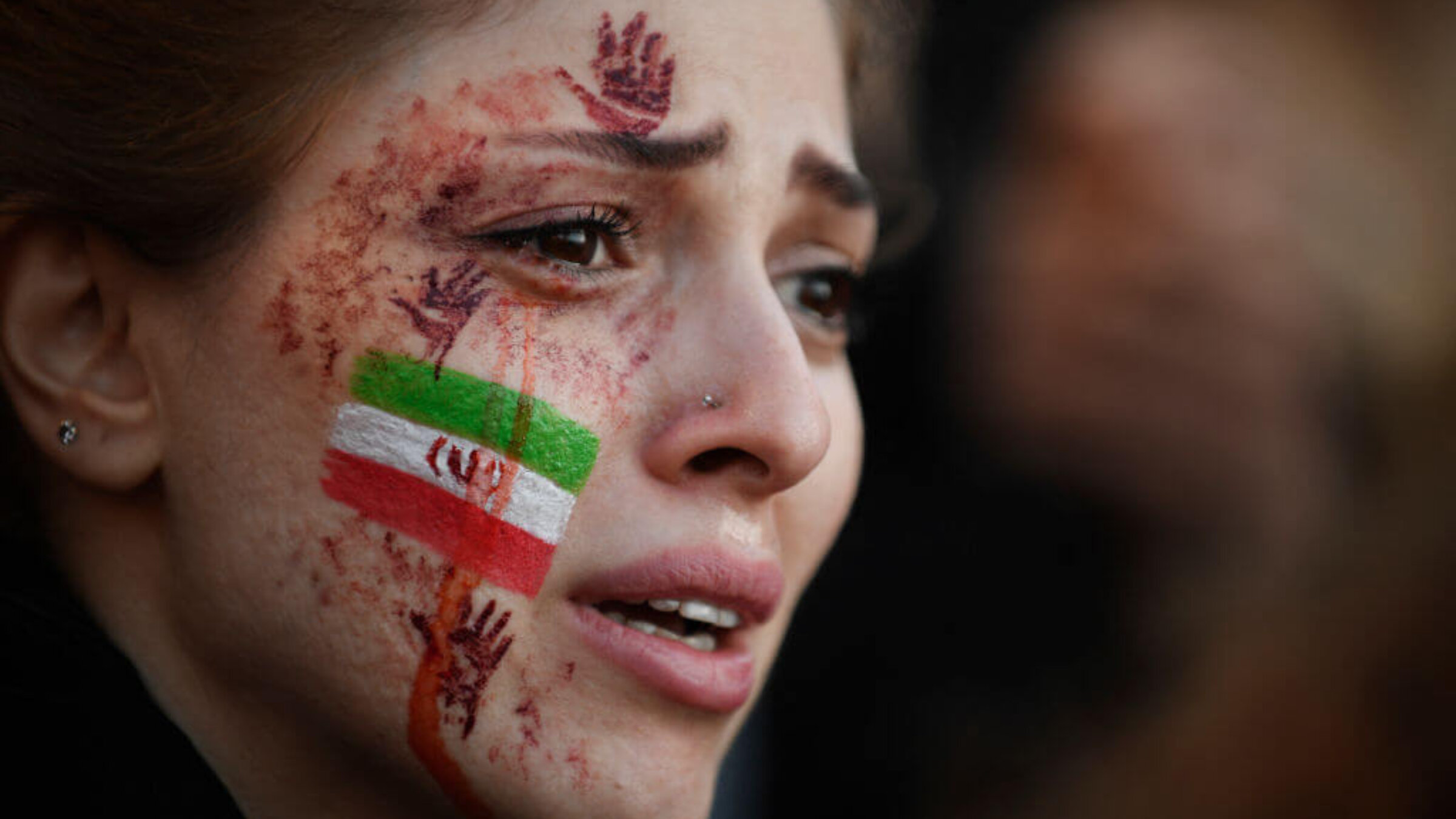 A demonstrator with an Iranian flag and red hands painted on her face attends a rally in support of Iranian protests in Paris on Oct. 9, 2022, following the death of Iranian woman Mahsa Amini.