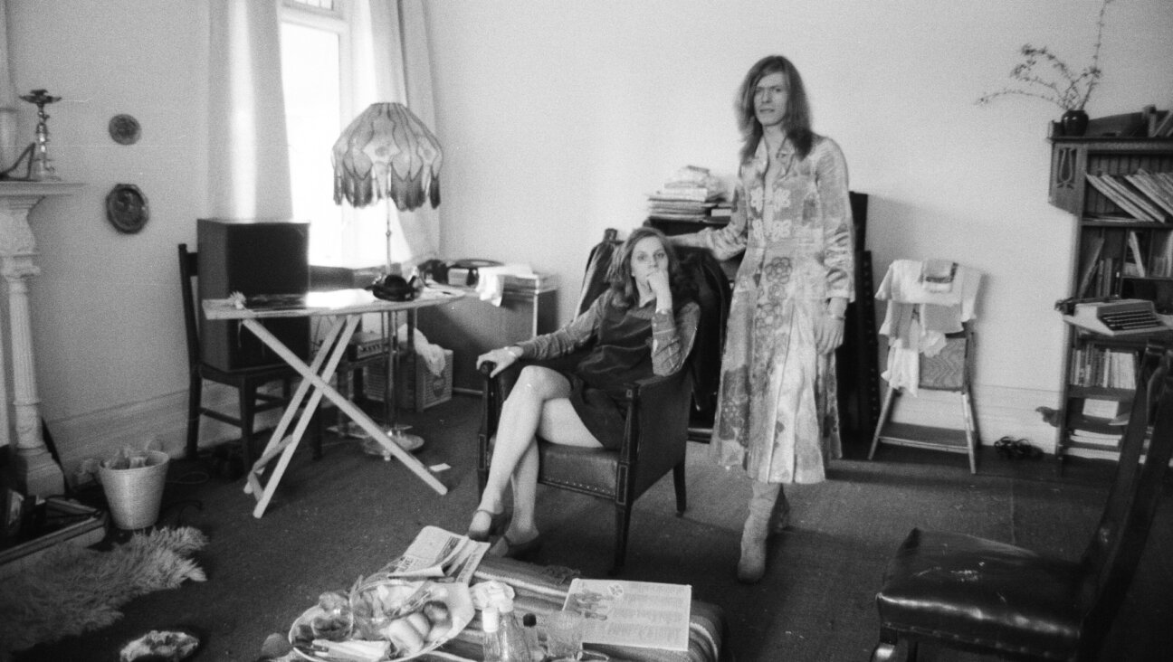David Bowie, shown with his wife Angie at home in Kent, England, in 1971, is wearing a dress that he famously wore on the cover of his “The Man Who Sold the World” album. (Peter Stone/Mirrorpix/Getty Images)
