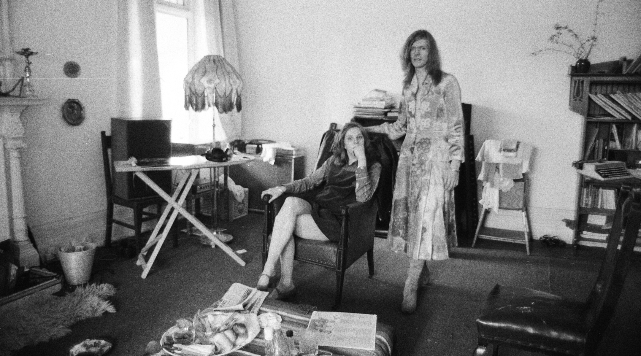 David Bowie, shown with his wife Angie at home in Kent, England, in 1971, is wearing a dress that he famously wore on the cover of his “The Man Who Sold the World” album. (Peter Stone/Mirrorpix/Getty Images)