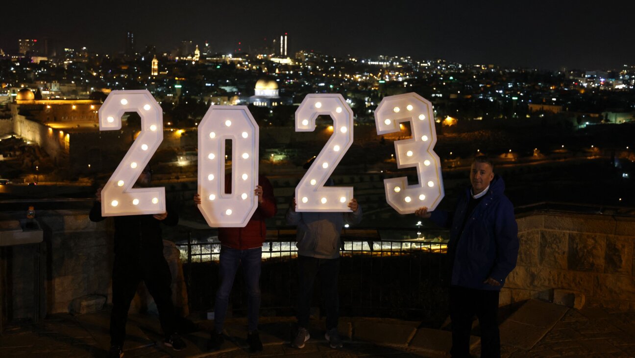 People pose for a picture with a lit up 2023 sign at the Mount of Olives in Jerusalem on Dec. 31, 2022.