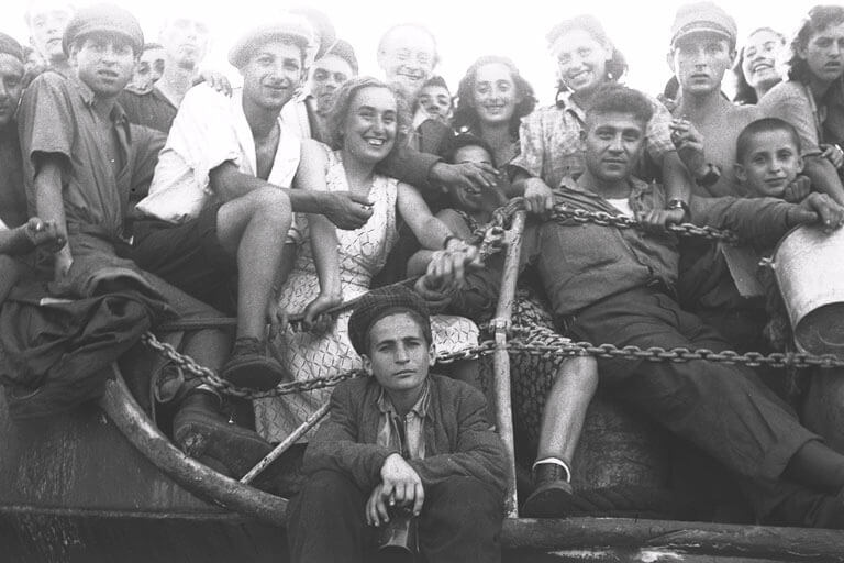 A crowd of Jewish immigrants smile as they arrive at Haifa harbor in 1947. 