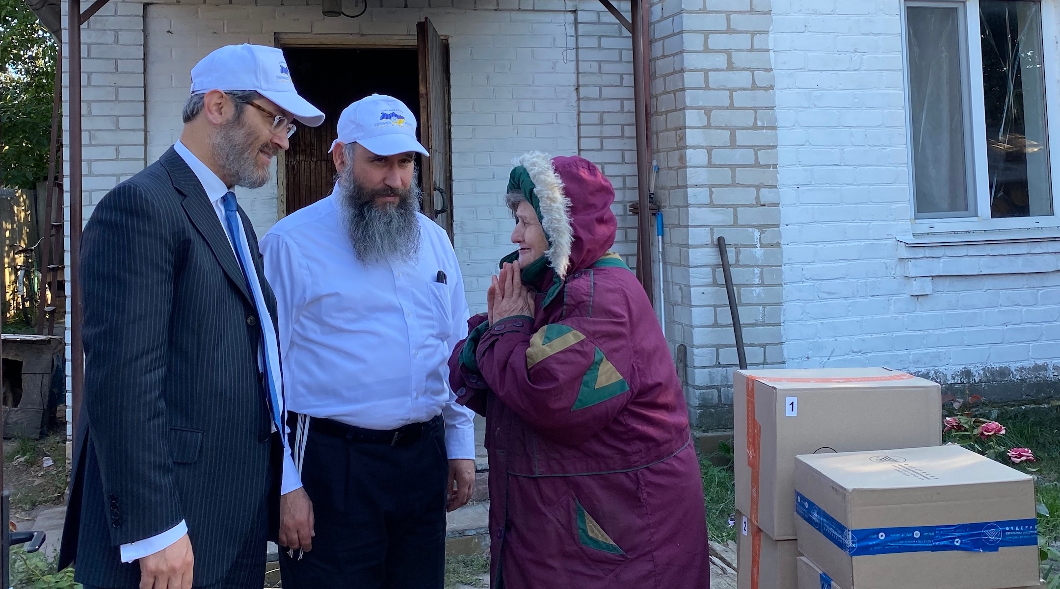 Rabbis Raphael Rotman, left, and Meir Stambler, both from the Federation of Jewish Communities of Ukraine, deliver boxes to an elderly non-Jewish Ukrainian woman in Bucha who has been receiving their aid for months. (Jacob Judah)