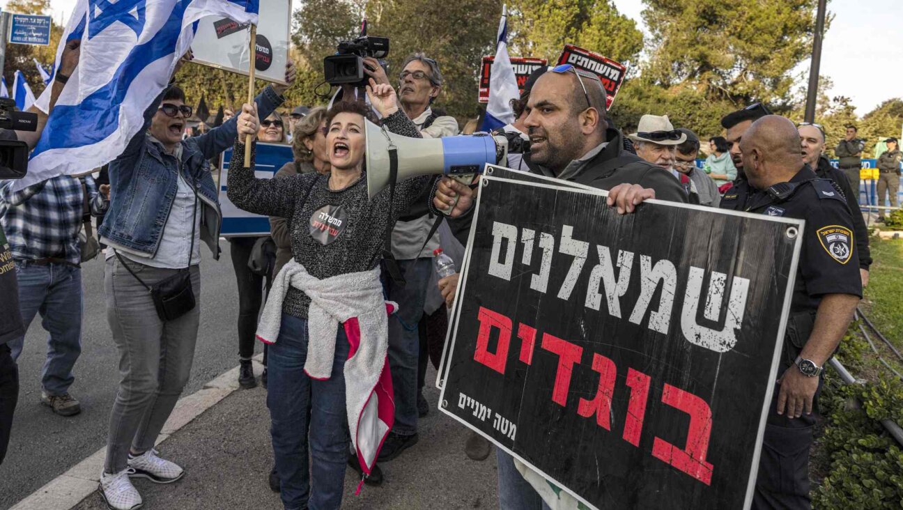 A right-wing activist, carrying a sign that reads “leftist traitors,” confronts left-wing activists at an anti-government demonstration near the Knesset in Jerusalem, Dec. 12, 2022. (MENAHEM KAHANA/AFP via Getty Images)