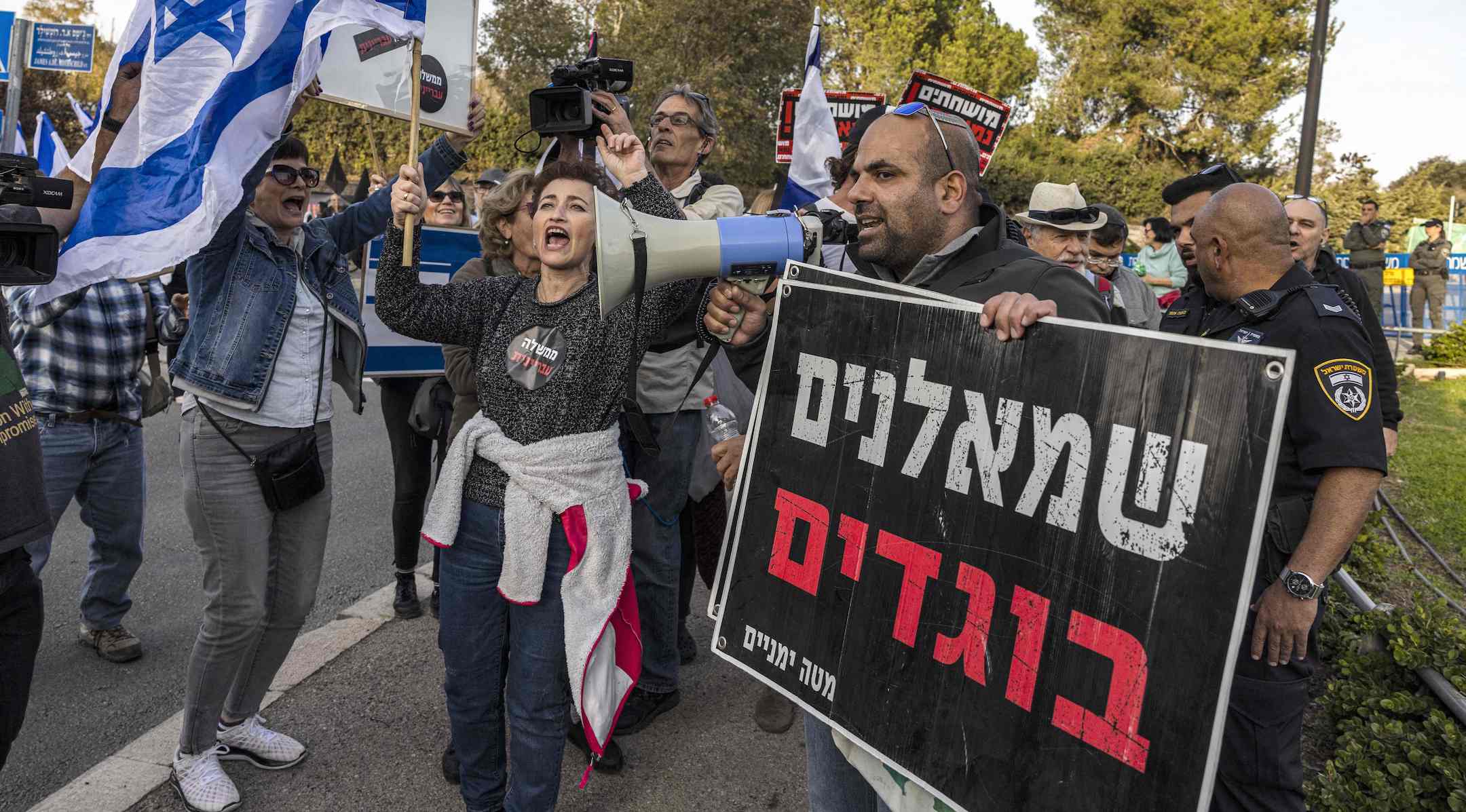 A right-wing activist, carrying a sign that reads “leftist traitors,” confronts left-wing activists at an anti-government demonstration near the Knesset in Jerusalem, Dec. 12, 2022. (MENAHEM KAHANA/AFP via Getty Images)