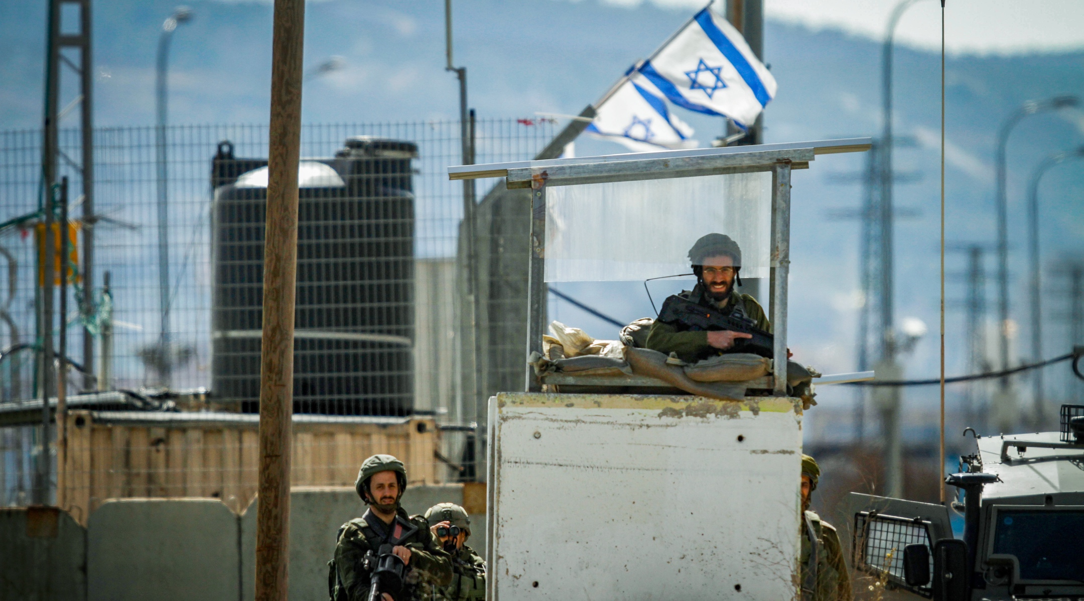 Israeli soldiers guard as Palestinians protest at the Hawara checkpoint, south of the West Bank city of Nablus, Feb. 10, 2022. (Nasser Ishtayeh/Flash90)