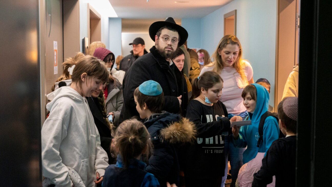 Rabbi Mendy Wolff stands in a hallway in a hotel among children he brought from a Jewish orphanage in Odessa, Ukraine. (Christophe Gateau/picture alliance via Getty Images)