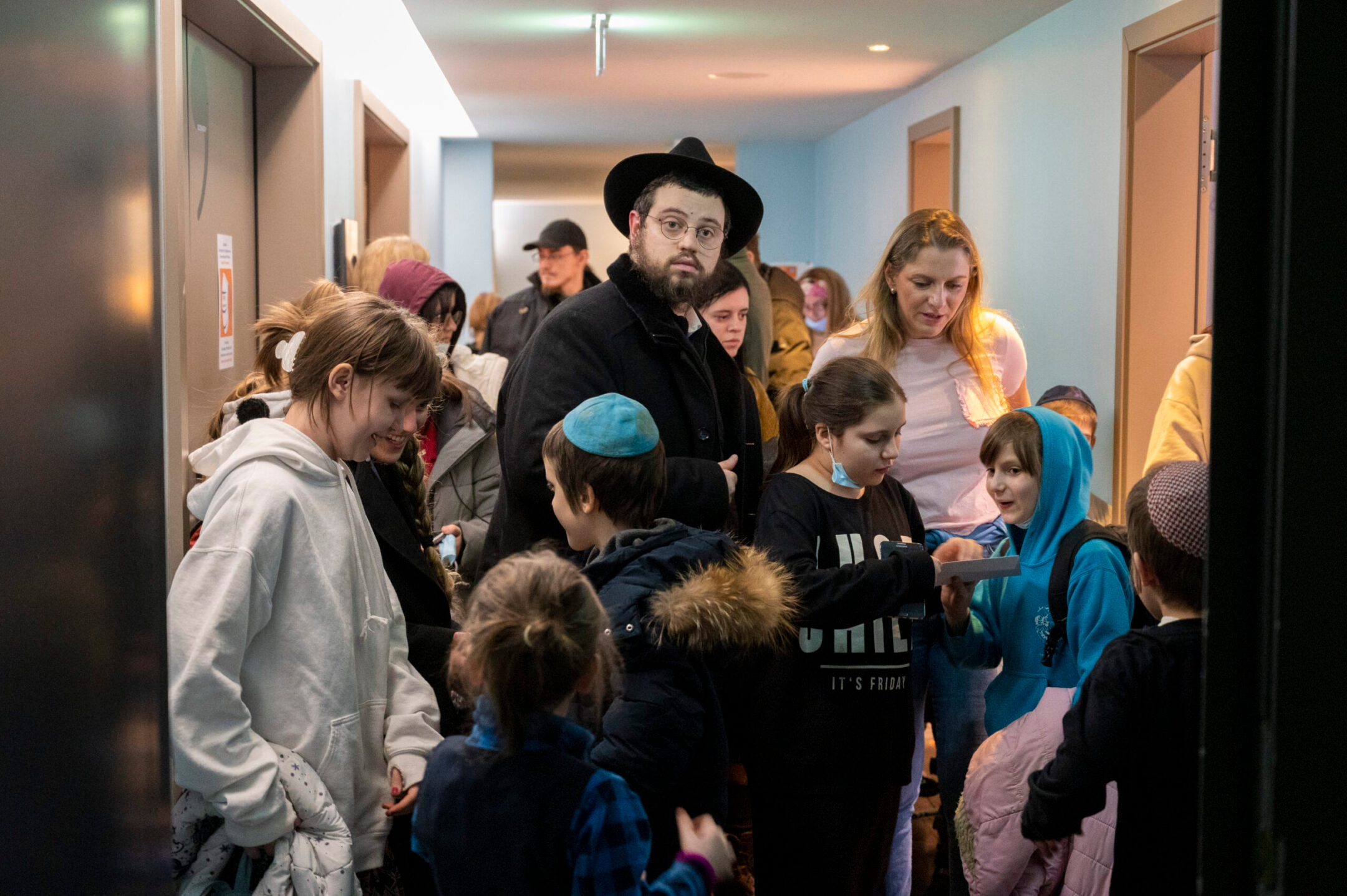 Rabbi Mendy Wolff stands in a hallway in a hotel among children he brought from a Jewish orphanage in Odessa, Ukraine.