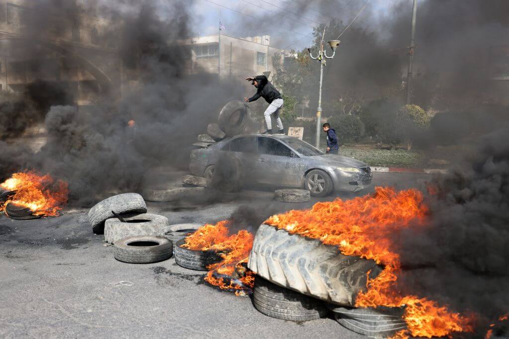 Palestinian protesters burn tires to block a road leading into Jericho in the occupied West Bank, on February 6, 2023, following a raid in town by Israeli forces that killed at least five Palestinian militants.