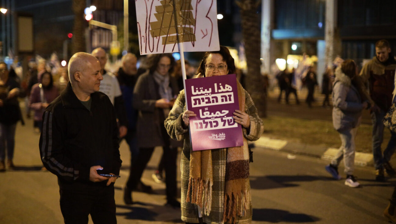 A lone protester advocating in Hebrew and Arabic for coexistence participates in a protest against planned changes to Israel’s judicial system, Tel Aviv, Feb. 11, 2023. (Saeed Qaq/Anadolu Agency via Getty Images)
