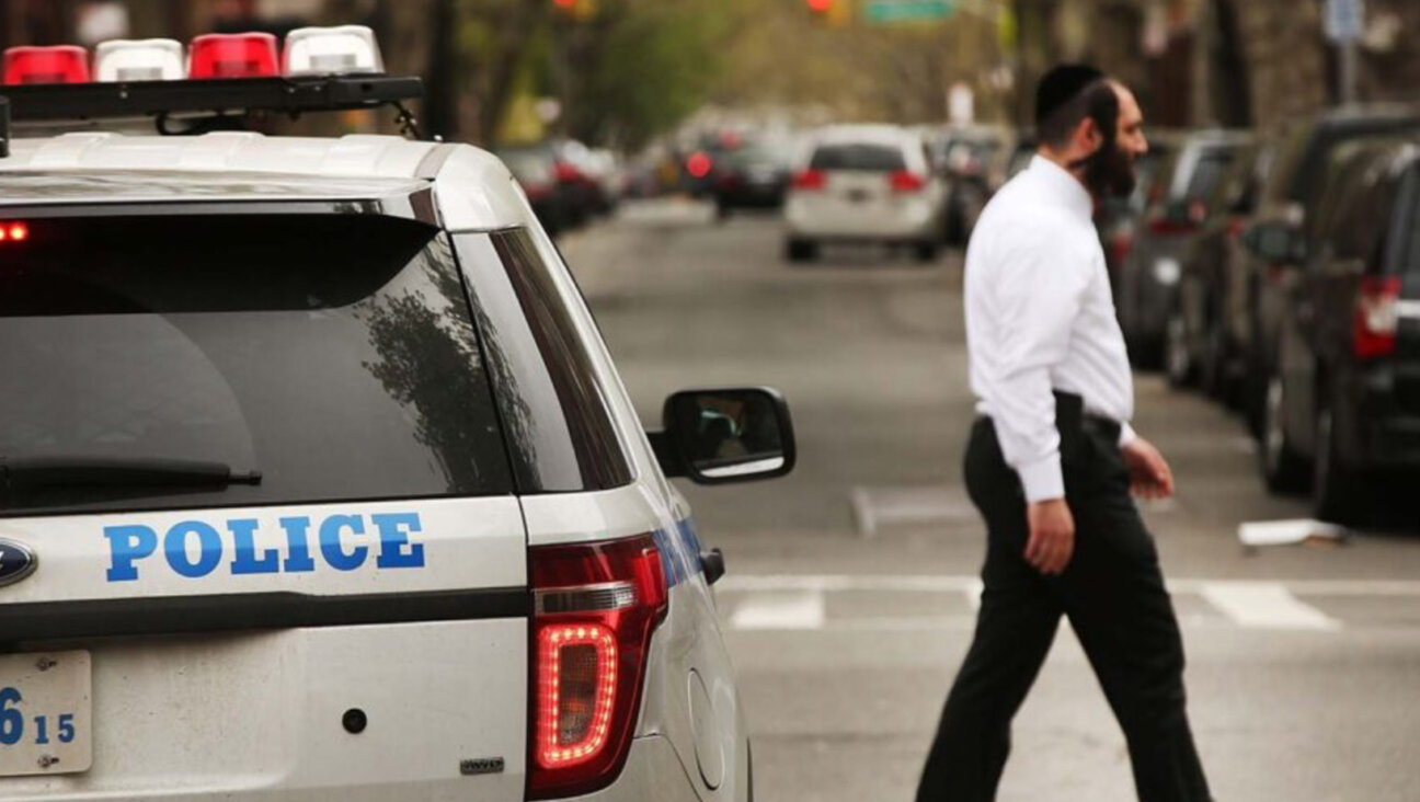 A Hasidic man walks by a police car in a Jewish Orthodox neighborhood in Brooklyn, April 24, 2017. (Photo Credit: Spencer Platt/Getty Images)