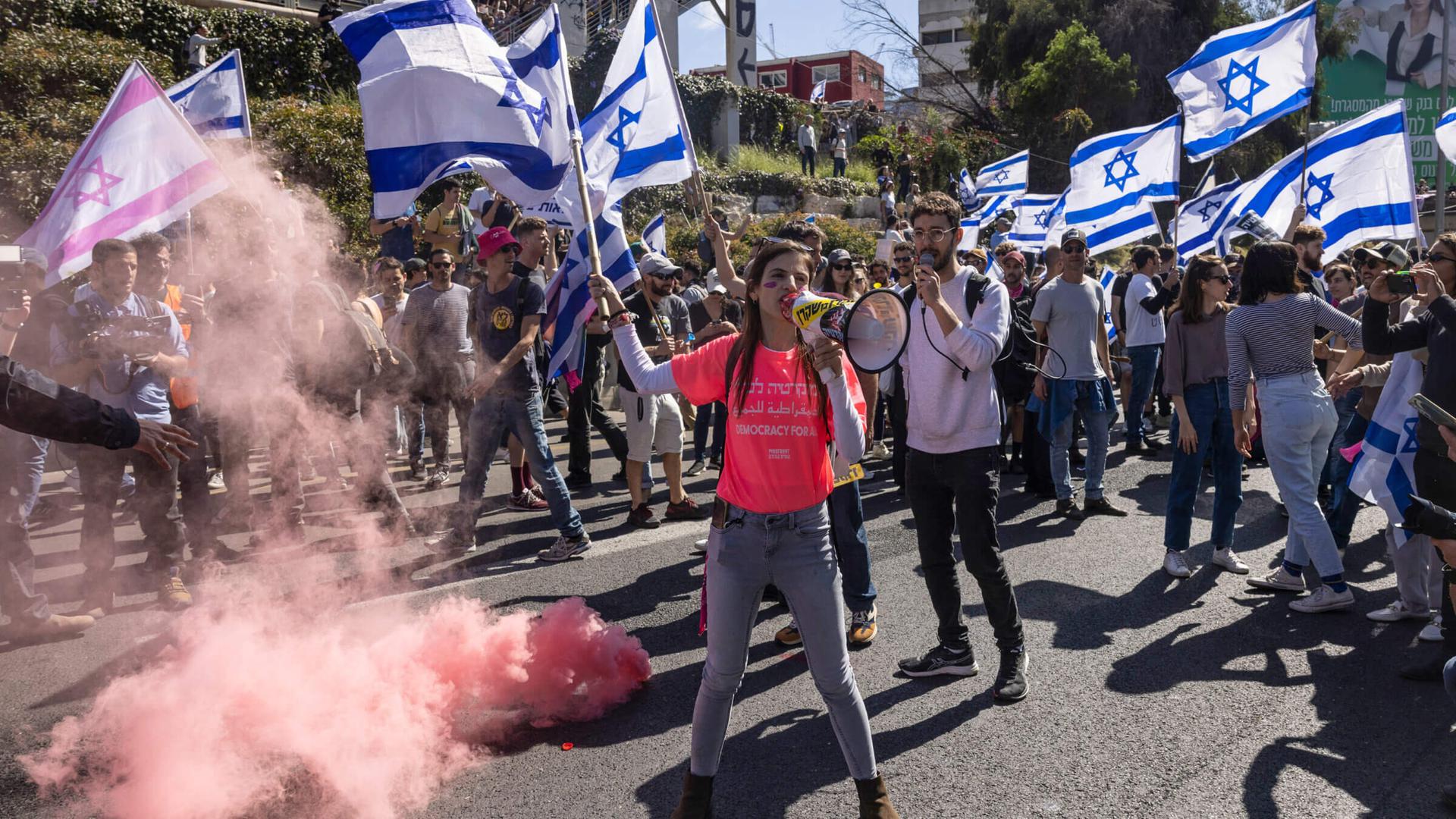 Tech workers wave flags and set off smoke bombs during a protest in Tel Aviv. 