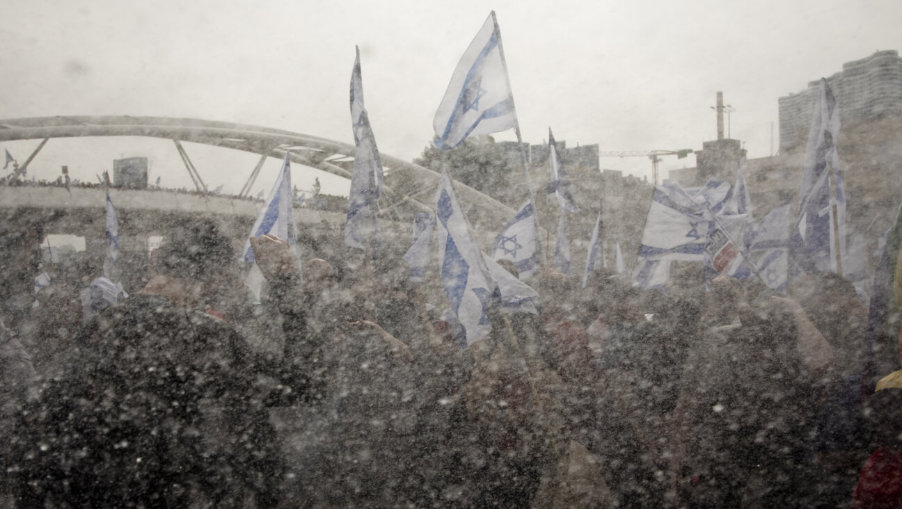 Israeli protesters hold the Israeli flag as Israeli police use a water cannon to evacuate protesters from a main highway during a rally against the Israeli government's judiciary overhaul on March 23, 2023 in Tel Aviv, Israel