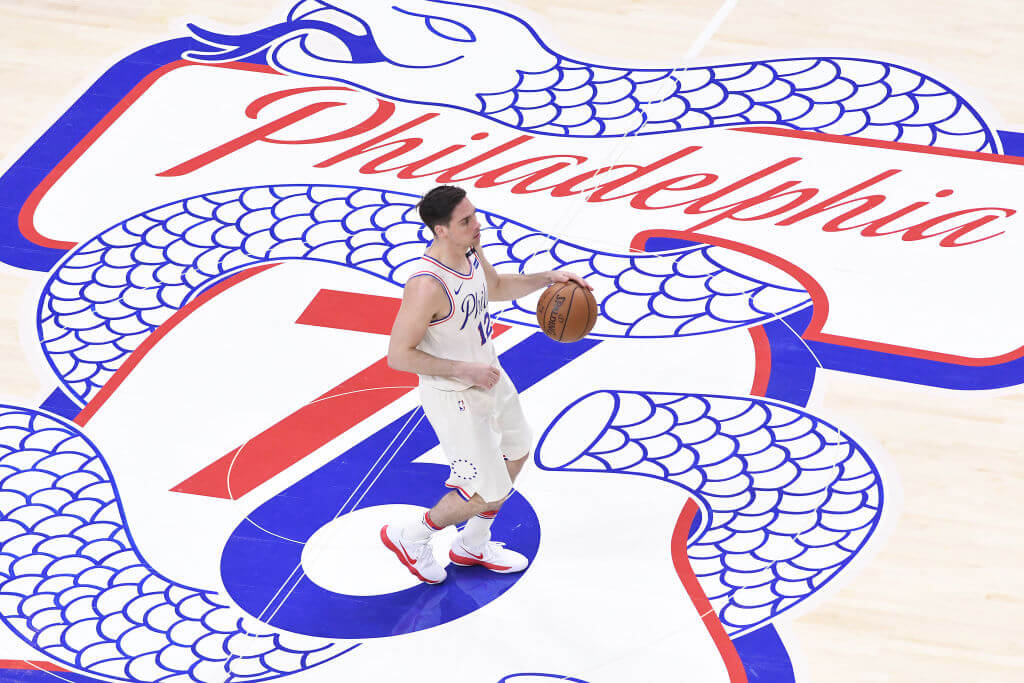 T.J. McConnell of the Philadelphia 76ers brings the ball past the "Phila Unite" logo in the 2018 NBA Playoffs.