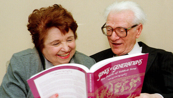 Chana and Yosl Mlotek with one of their signature Yiddish songbooks, "Songs of Generations"