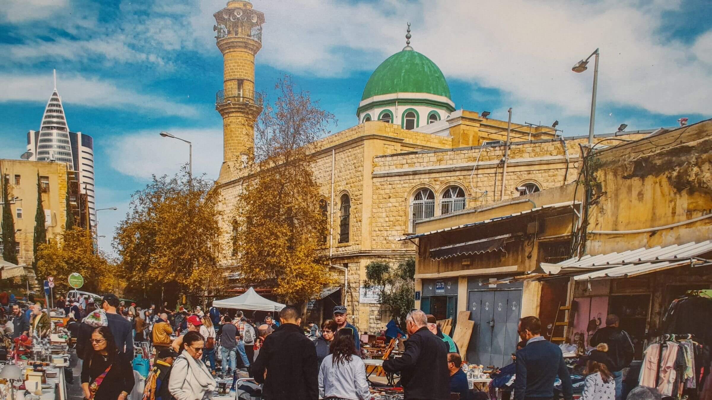 A flea market in Haifa, known locally as Shuk Pishpeshim. Behind it is the Al Istiqlal Mosque.