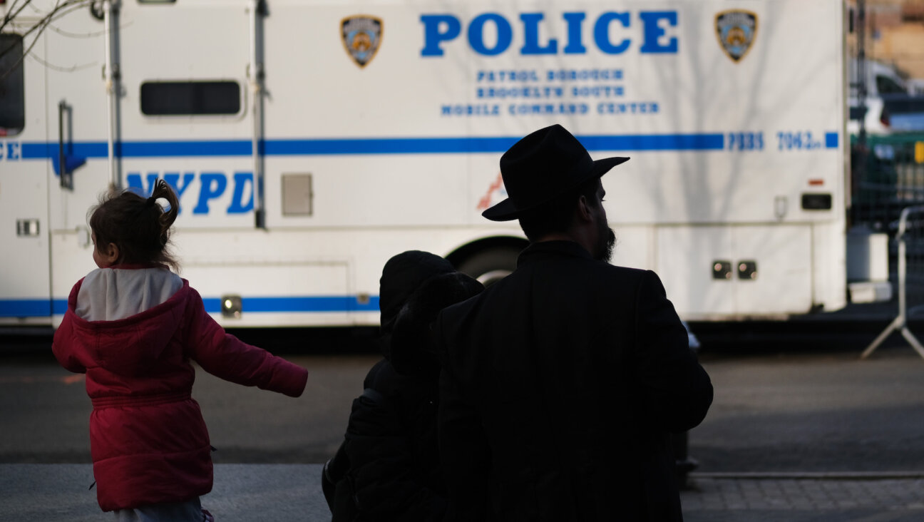 A man and girl in the Crown Heights neighborhood of Brooklyn stand opposite a police van, Dec. 31, 2019. Brooklyn was the location of more than one-third of the total number of anti-Semitic assaults committed last year, according to the Anti-Defamation League. 