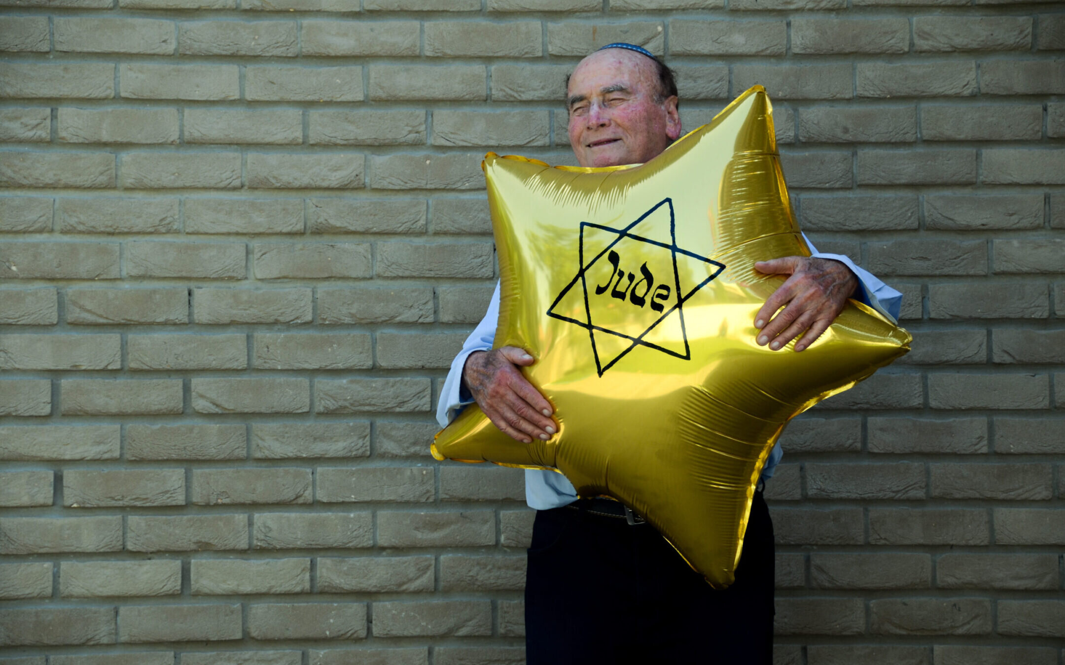Dugo Leitner, a survivor of Auschwitz-Birkenau, holds a balloon shaped like the Jewish star that the Nazis forced Jews to wear. (Erez Kaganovitz)