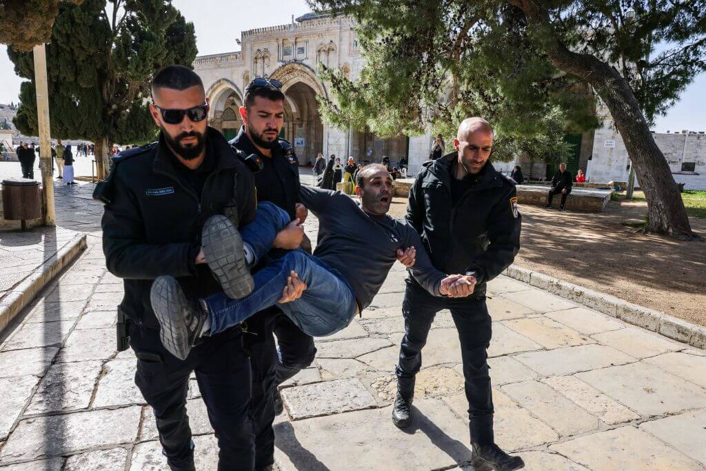 Israeli policemen detain a Palestinian man at the Al-Aqsa Mosque compound following clashes that erupted on April 5, 2023.