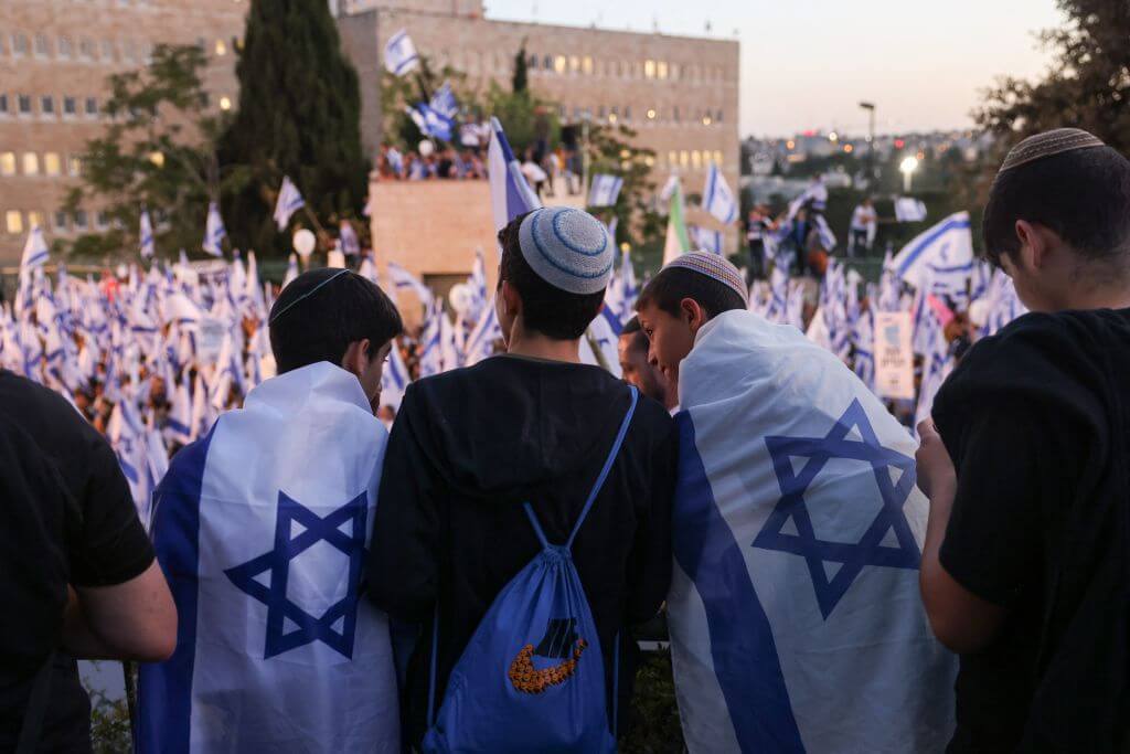 Pro-government protesters wave the Israeli flag as they gather near Israel's parliament in Jerusalem on April 27, 2023 in support of the hard-right government's controversial push to overhaul the justice system.