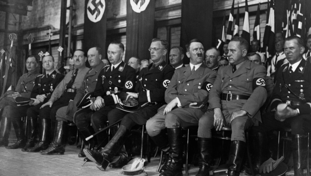 Arthur Seyss-Inquart, wearing glasses, is seated in the front row to the left of Adolf Hitler at a rally with Nazi officials. 