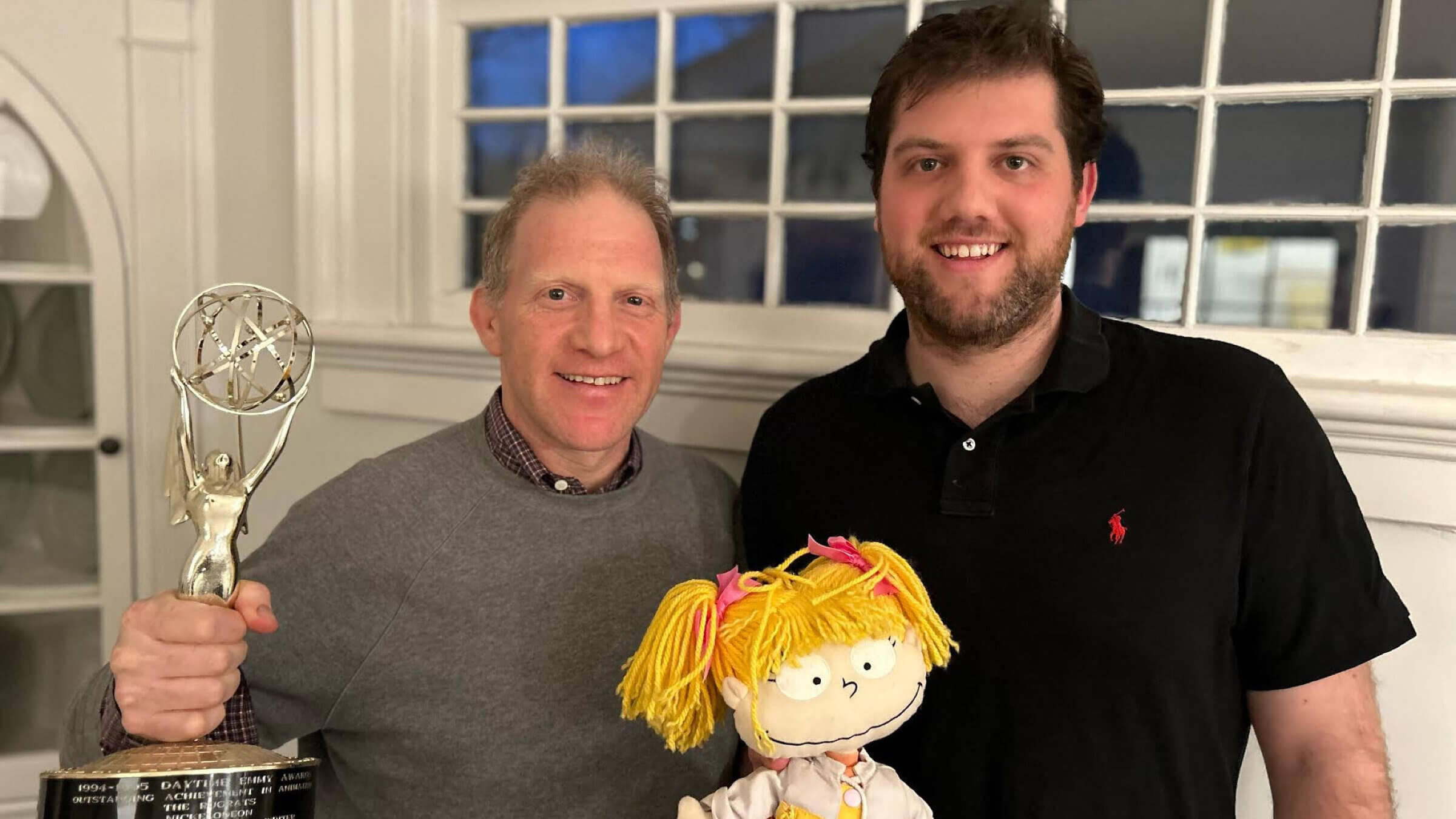 Jonathan Greenberg, left, with the Daytime Emmy Award for the  the Rugrats Passover episode, which he co-wrote, and his son Hank Greenberg. They stand before a stuffed version of Angelica, a Rugrats character.