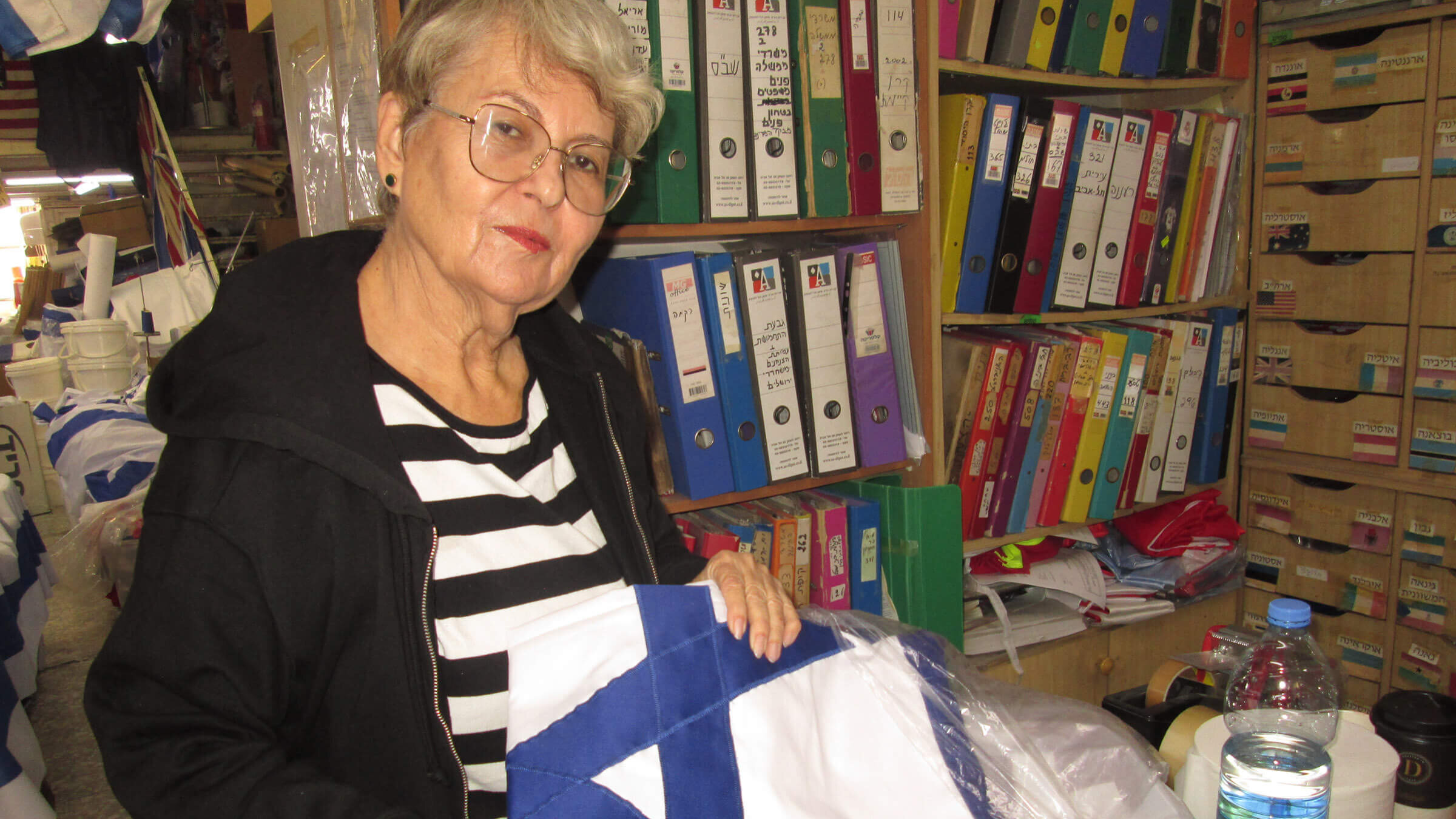Hadassah Berman, the 75-year-old daughter-in-law of company's founders, holds a flag whose Star of David is hand-sewn onto the fabric. 