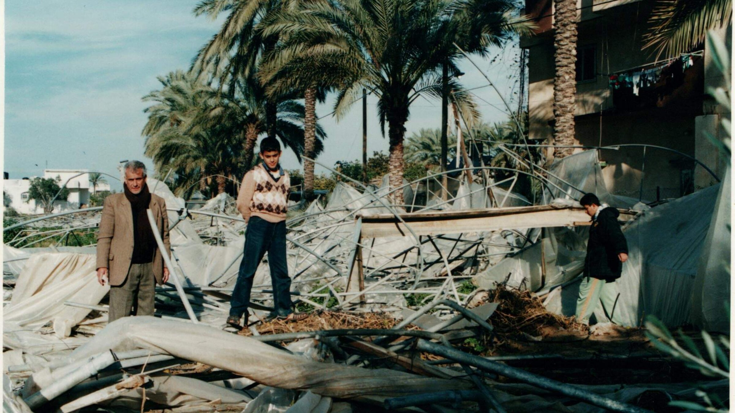 The author and his father, Khalil, at home in Gaza examining the destruction of their family's greenhouses by Israeli soldiers.