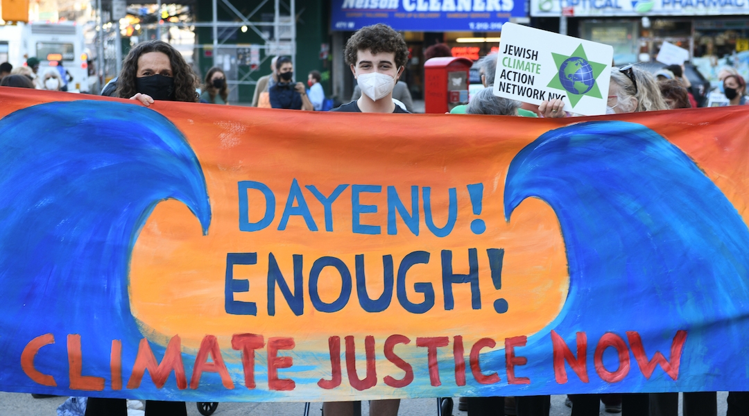 Dayenu CEO Jennie Rosenn holds up a banner after addressing the crowd at a rally urging New York State lawmakers to pass the Climate and Community Investment Act in New York, April 7, 2021. (Gili Getz / Courtesy of Dayenu)