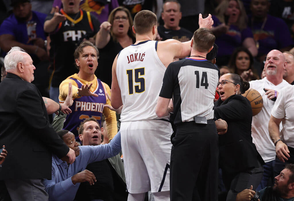 Nikola Jokic (15) of the Denver Nuggets reaches for the basketball after pushing off Phoenix Suns owner Mat Ishbia (left, in black shirt) during Sunday's Game Four of the Western Conference semifinals. The Suns defeated the Nuggets 129-124.