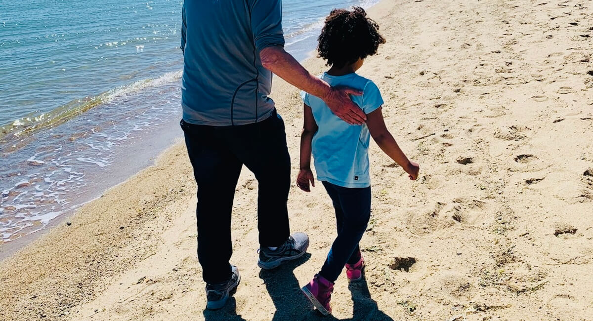 The author's Black Jewish daughter and her grandfather walk alongside the ocean