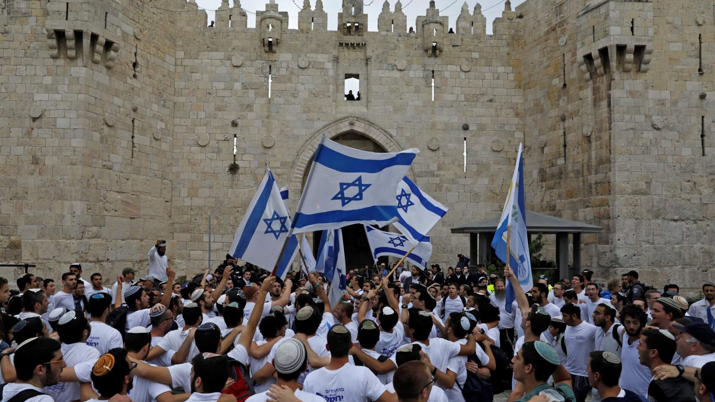 Israeli nationalist settlers wave their national flag as they celebrate the Jerusalem Day at the Old City's Damascus gate in Jerusalem on May 13, 2018. 