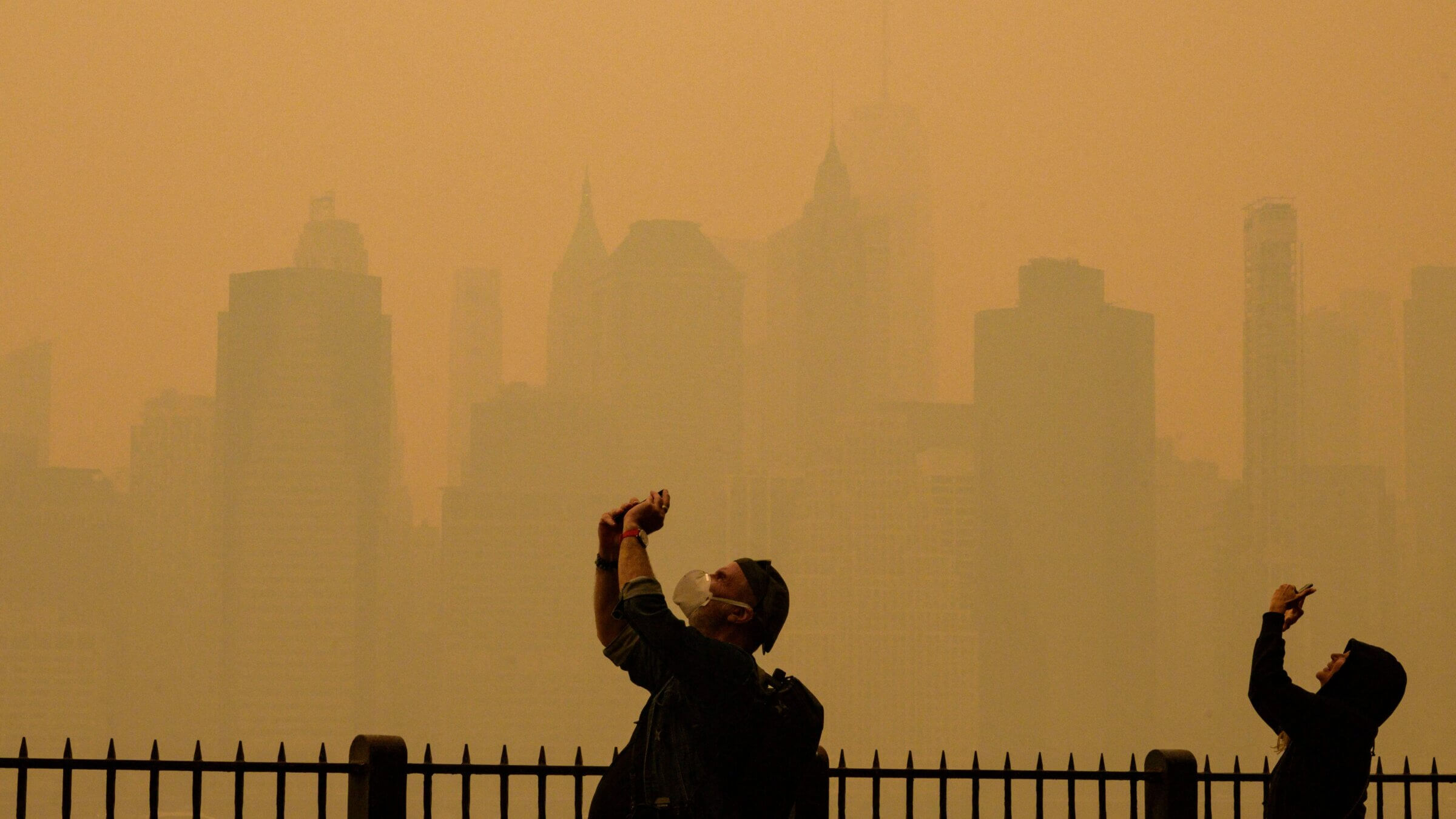 People take photos of the sun as smoke from the wildfires in Canada cause hazy conditions in New York City.