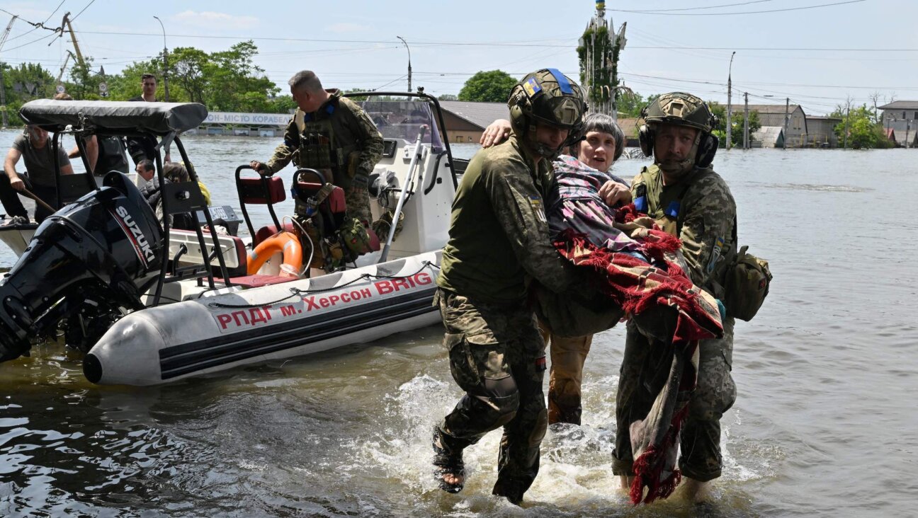 Ukrainian servicemen help a local resident during an evacuation from a flooded area in Kherson, Ukraine, June 8, 2023. (Genya Savilov/AFP via Getty Images)