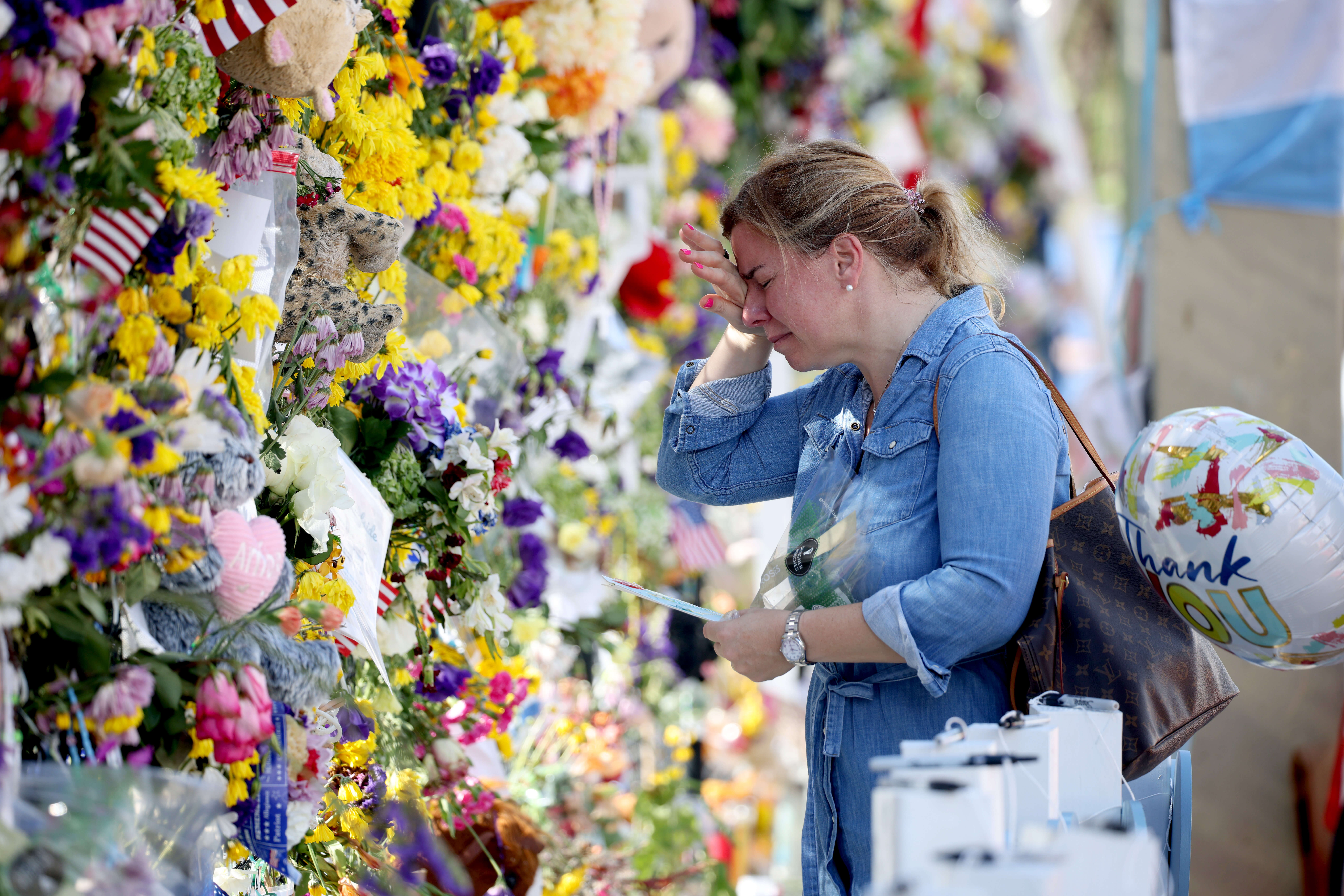 A visitor weeps as she places flowers near the memorial site for victims of the collapsed 12-story Champlain Towers South condo building on July 8, 2021, in Surfside, Florida. 