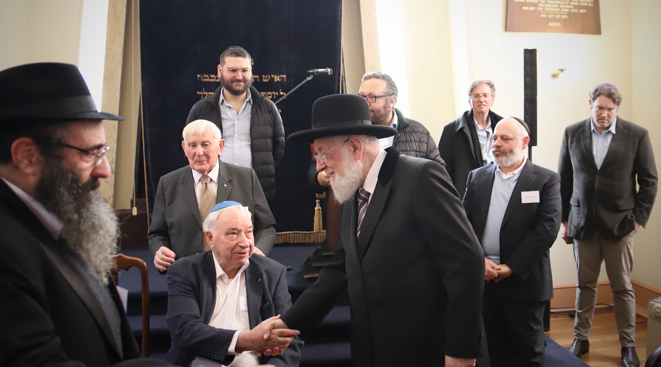 Israel’s former Chief Ashkenazi Rabbi Yisrael Meir Lau shakes hands with Holocaust survivor Felix Goldschmied at the Launceston Synagogue in Launceston, Australia, July 12, 2023. (Mishka Gora)