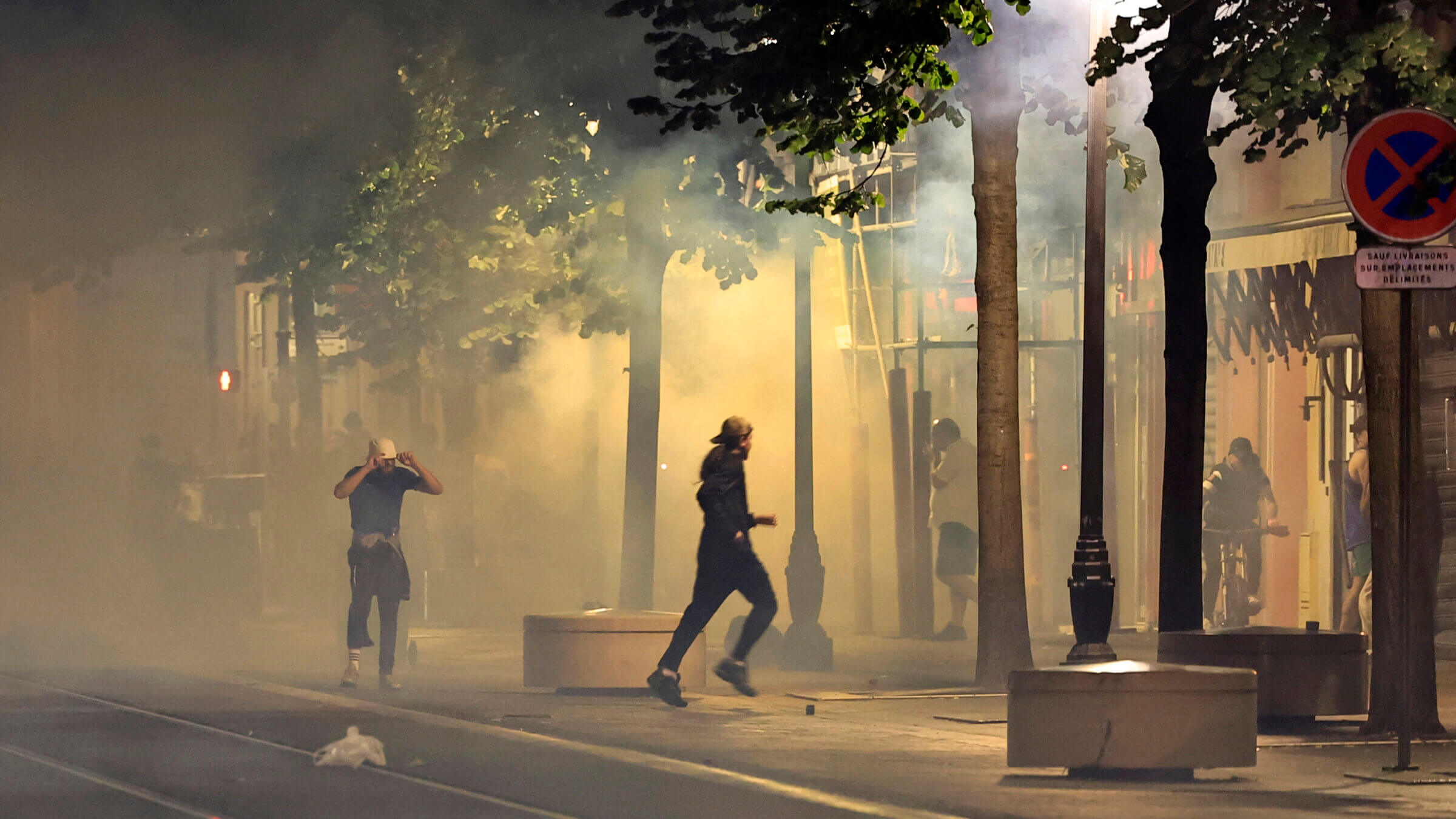 Protestors flee from smoke on a street in Nice,  France early July 2, 2023, during the fifth night of rioting following the shooting of a teenage driver in the Parisian suburb of Nanterre on June 27. 