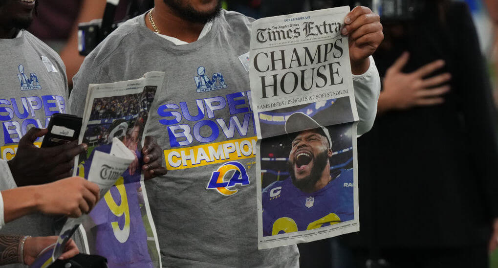 A Los Angeles Rams player holds up the <i>Los Angeles Times Extra</i> sports section following the Super Bowl in 2022.