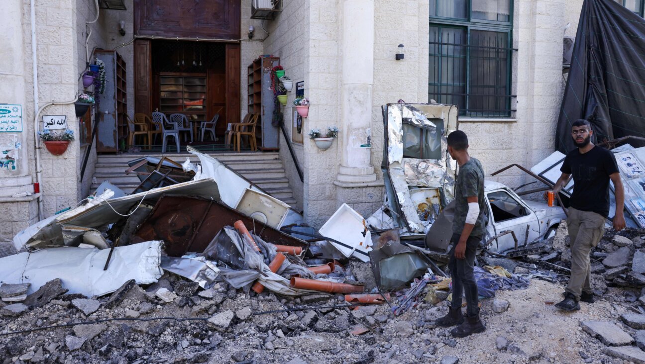 Men walk among rubble in front of a building in the occupied West Bank city of Jenin on July 4, 2023.