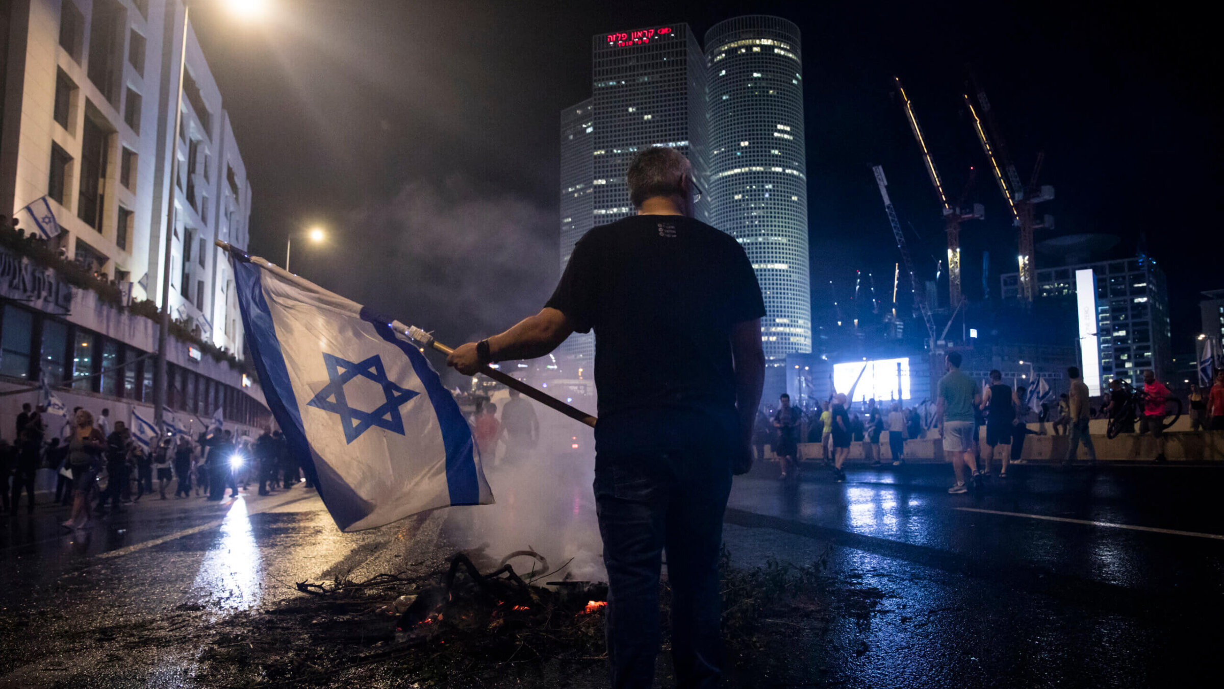 An Israeli man holds the Israeli flag during a demonstration against the Israeli government on July 5, 2023 in Tel Aviv, Israel. The protests followed an announcement from Tel Aviv's District Police Commander Ami Eshed that he was resigning from the police force after being ousted from his role by National Security Minister Itamar Ben-Gvir and Police Commissioner Kobi Shabtai, allegedly on political grounds.
