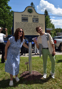 A photo showing photographers Marisa Scheinfeld and Isaac Jeffreys posing in front of the newly unveiled Mountain Dale historical marker