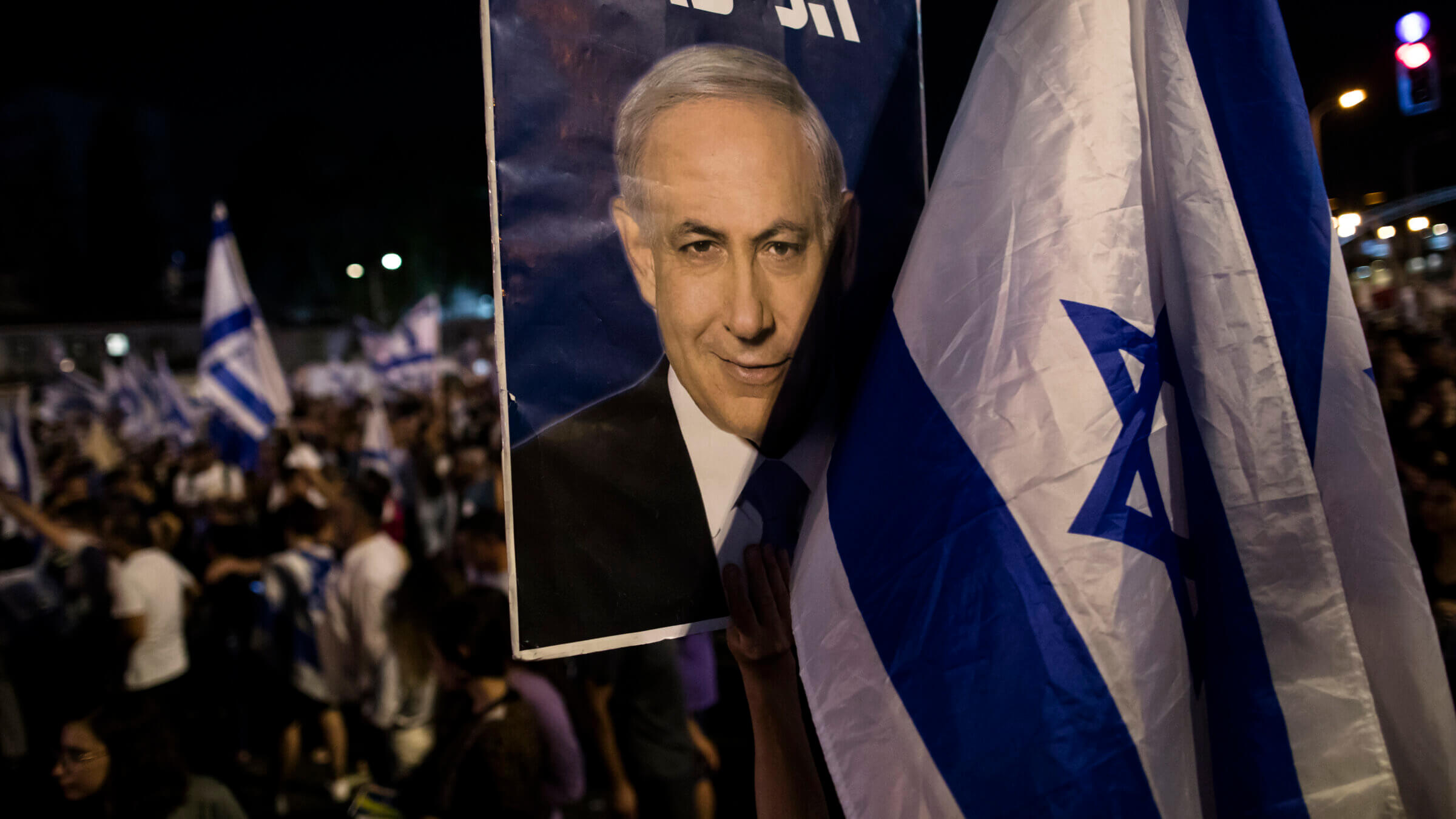 A woman holds a placard with a photo of Israeli Prime Minister Binyamin Netanyahu as the right wing holds a rally to support the government's judicial overhaul on July 23, 2023 in Tel Aviv.