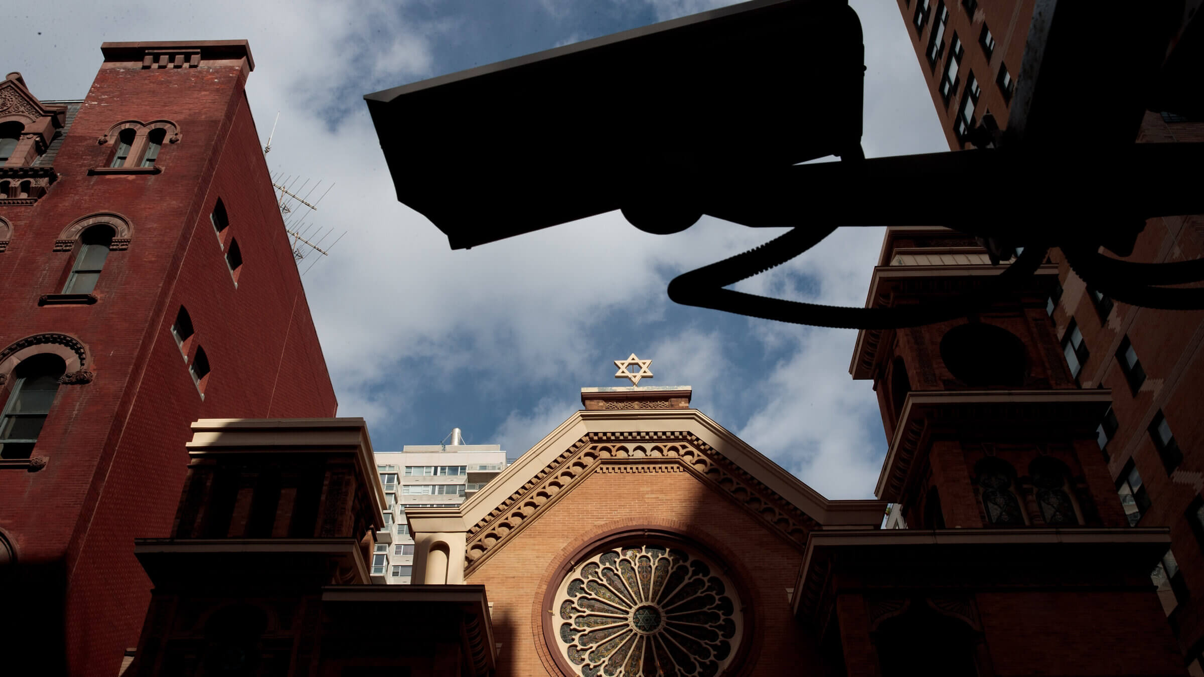 A security camera hangs across the street from the Park East Synagogue in New York City. Jewish institutions have been hit by a wave of swatting calls and bomb threats meant to disrupt services, and security experts have tips for how to stay safe during the High Holidays.