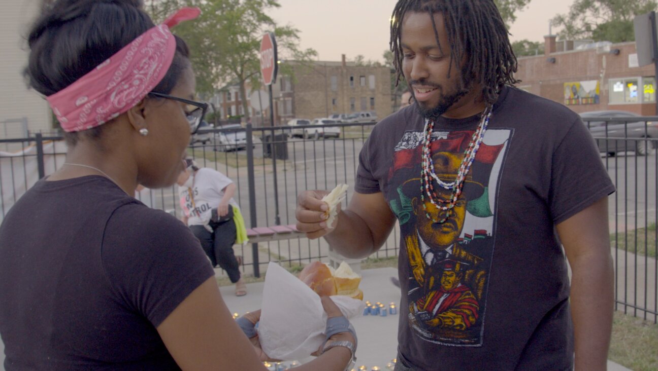 Rabbi Tamar Manasseh shares challah with a participant at the break-the-fast following a Yom Kippur service on a Chicago street corner in memory of victims of violent deaths during the previous year.