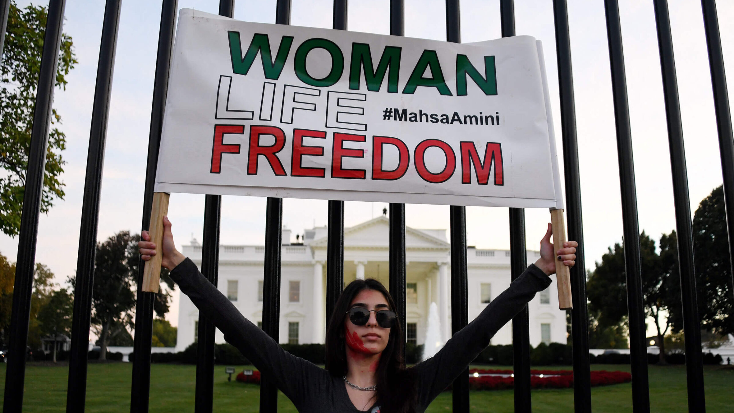 A woman holds a placard as protesters march in solidarity with protesters in Iran in front of the White House in Washington, DC, on October 22, 2022.