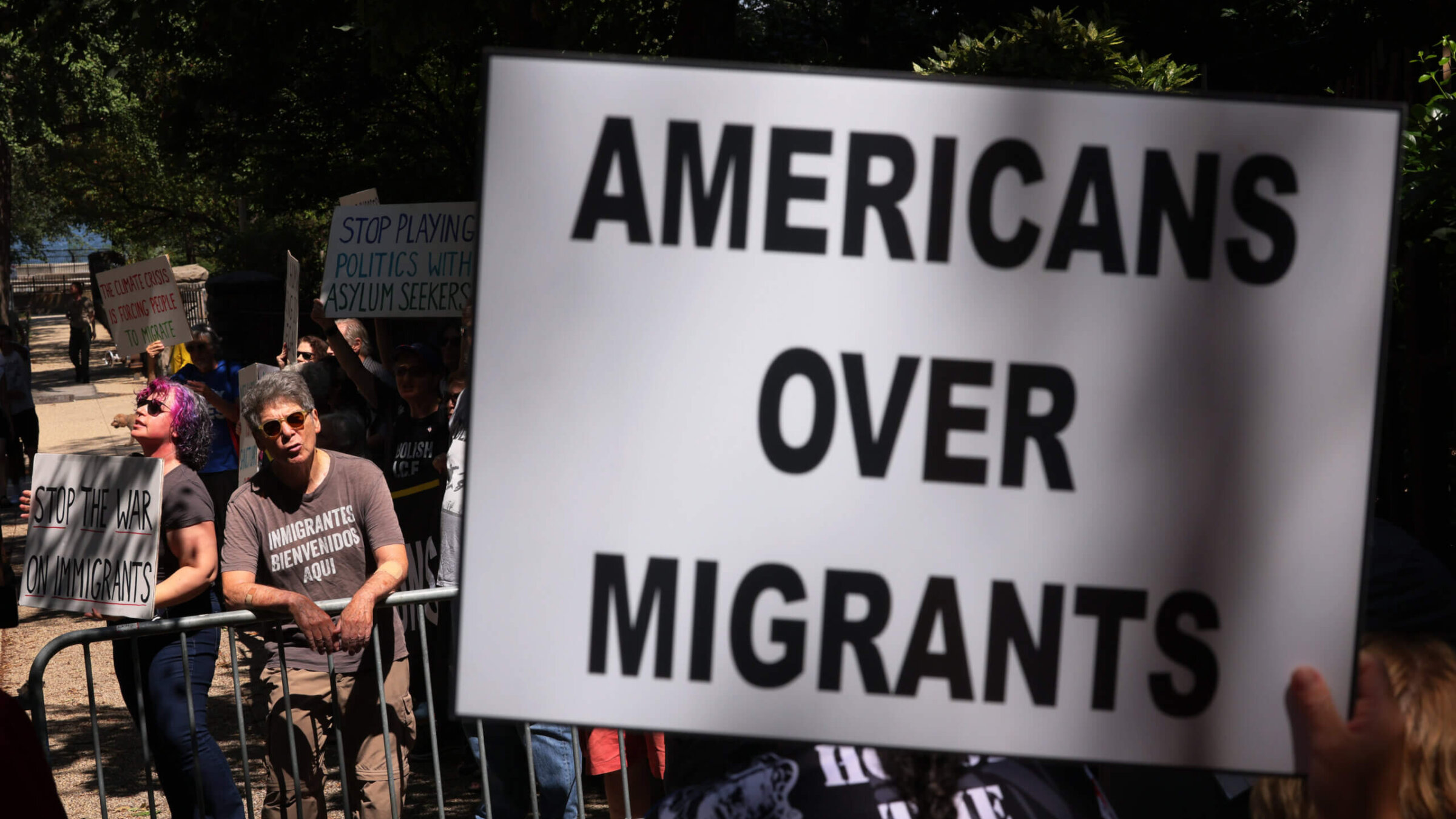 Counter protestors hold up signs as people participate in an anti-migrant rally and protest outside of Gracie Mansion on August 27, 2023 in New York City. 