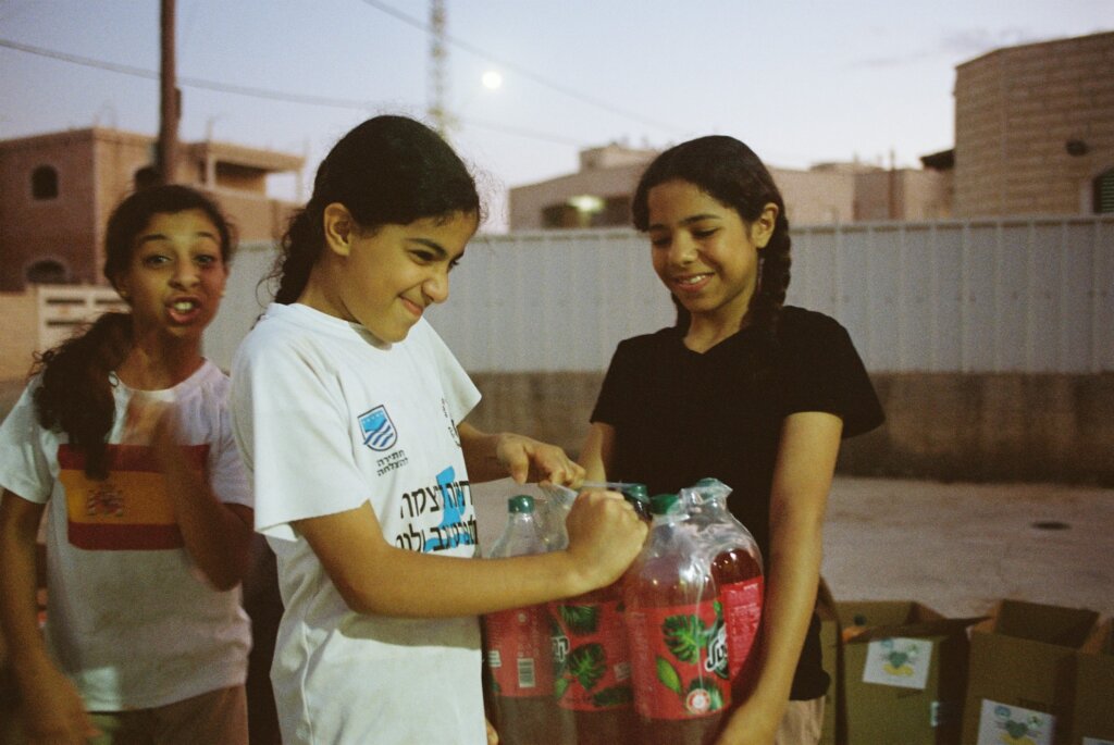 Three Bedouin girls in the Israeli town of Segev Shalom pack donations into boxes to distribute to families displaced by the war with Hamas