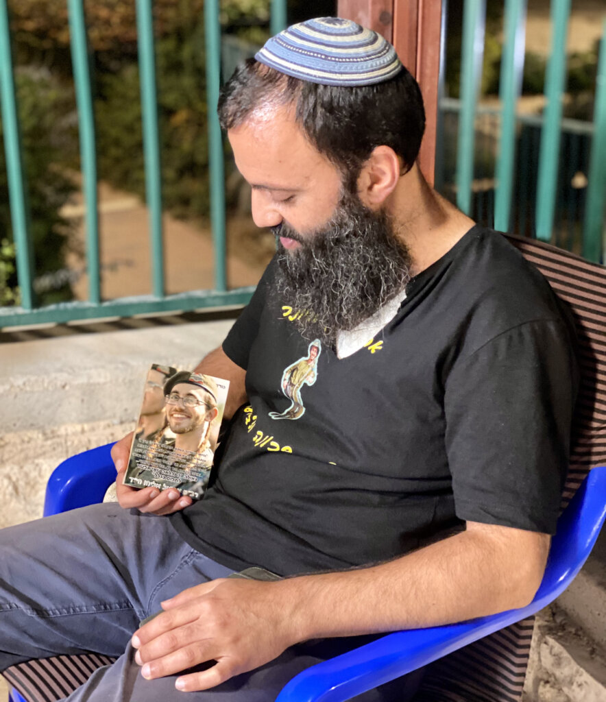 Rabbi Achiya Eliyahu looks down at a photo of his late son, Ariel, who was 19 when he died during active duty in the IDF.
