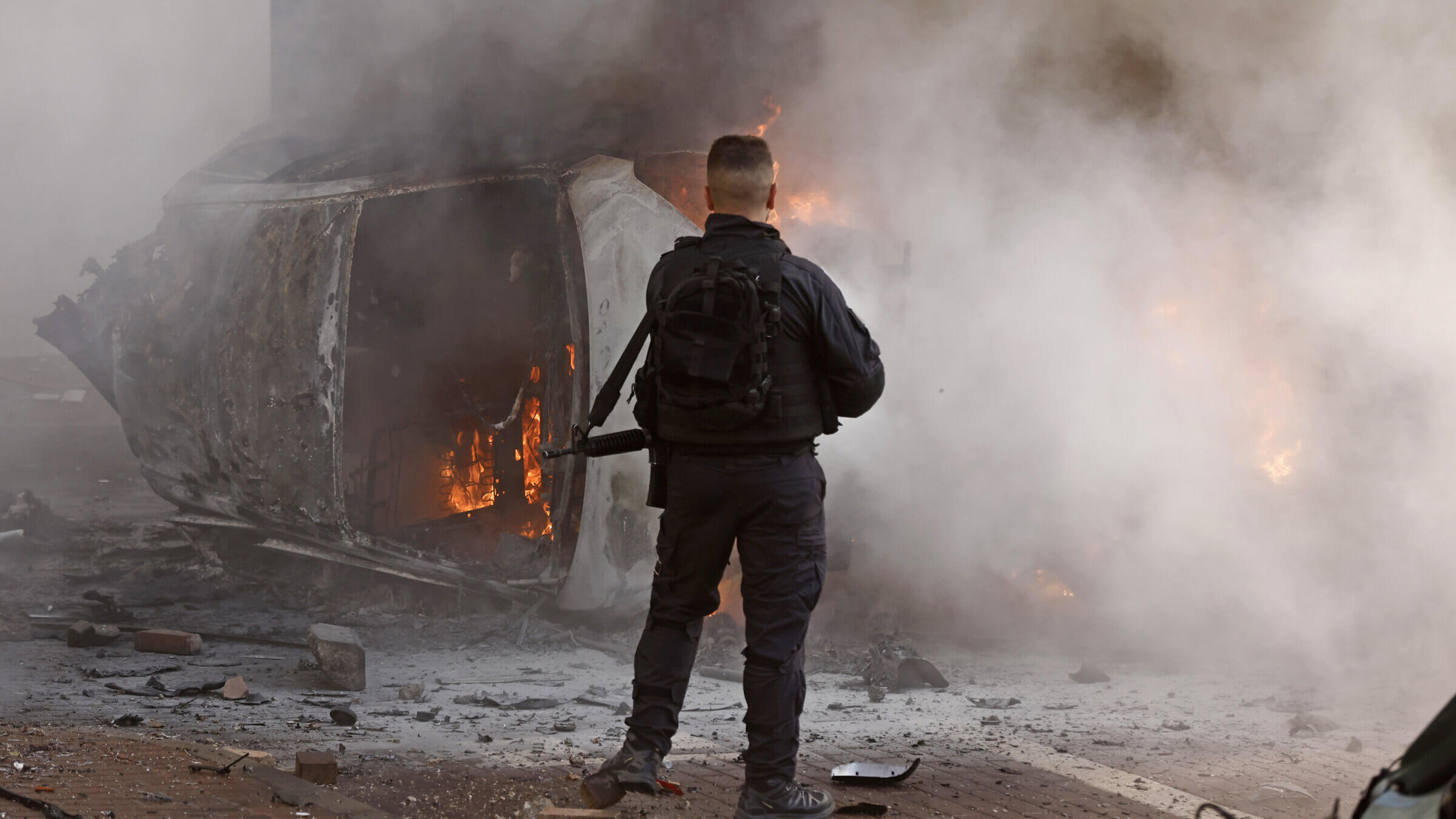 A man stands next to a burning car following a rocket attack in Ashkelon, Israel on Saturday, Oct. 7. 2023

